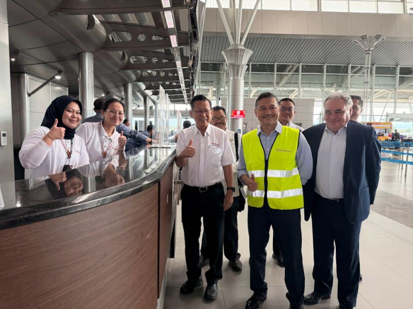 拿督斯里李景胜与AirBorneo职员在亚庇国际机场值机柜台合影。