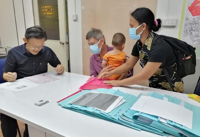  江仁贵夫妇（右）携带幼儿含泪面谢薛华东（左）助他俩长女（4岁）获得当局发予报生纸感人一幕。