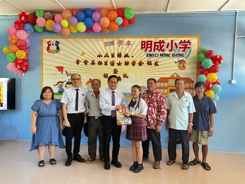 拿督吴标生（左四）颁发200令吉奖金和校方准备的礼物予明成小学2025年度模范生陈芯妤（左五）。