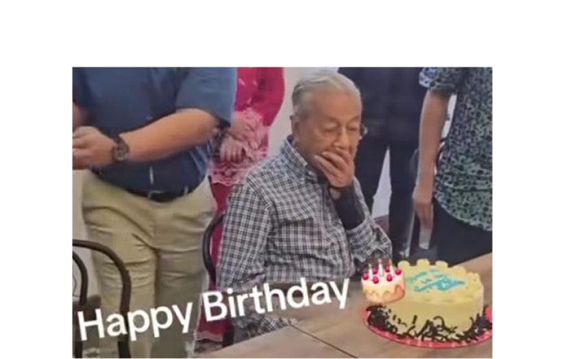 敦马哈迪看着友人献上的百岁生日蛋糕，难掩感动与惊喜。