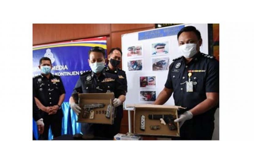 沙巴警察总监拿督哈扎尼(中)展示所卤获的枪支。