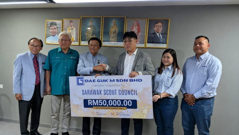 金相哲(右三)移交5万令吉企业赞助金予威廉玛旺（左三），左起为马来西亚童军总会砂拉越分会执行秘书扎斯兰，砂拉越童军首席总监林文明。右起为伯纳迪克马修及李格蕾丝李陪同见证。
