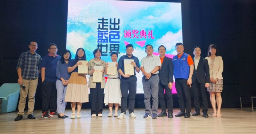 古晋南扶轮社及砂拉越星座诗社联办征文比赛得奖者与嘉宾合照。右四为古晋南区扶轮社社长黄永兴；右三为走出蓝色世界心理健康座谈会筹委会主席李鸿辉；右二为 国际扶轮3310区 社区服务组主委莫荣耀；右五为砂拉越星座诗社主席黄泽荣。